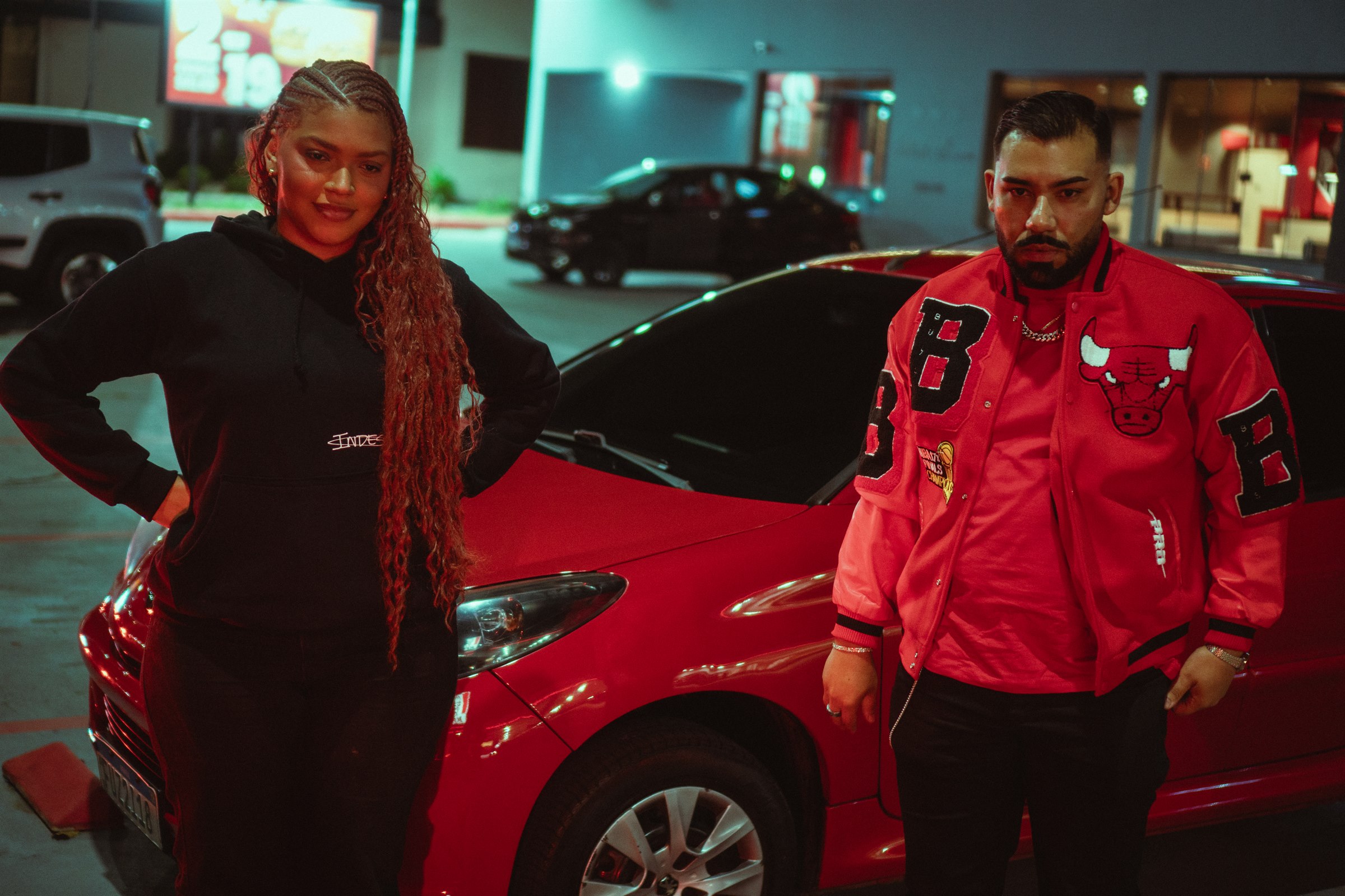 Jay Hoo e a modelo diante de um carro vermelho durante a gravação